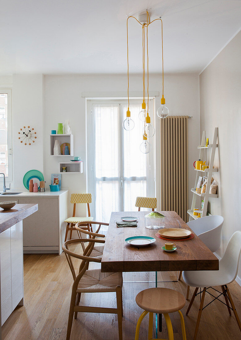 Dining table with wooden top on plexiglas base in bright, white kitchen with yellow accents