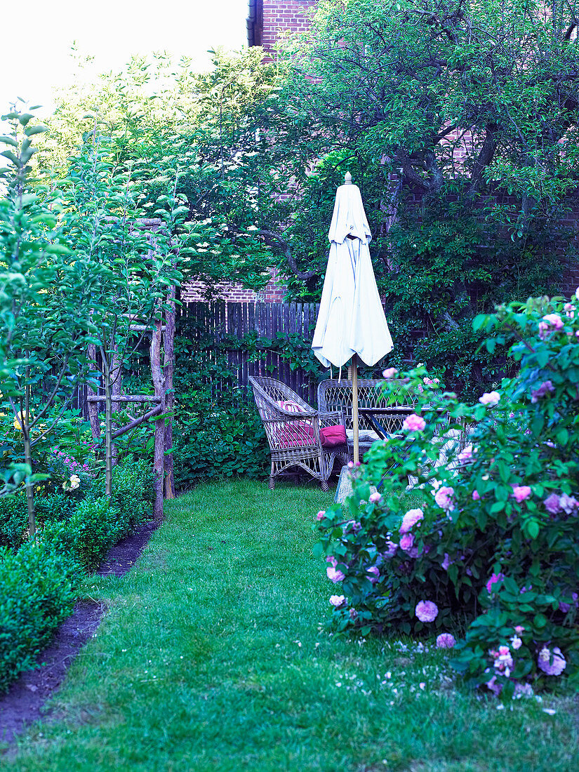 Sitzgruppe mit Sonnenschirm am Gartenzaun