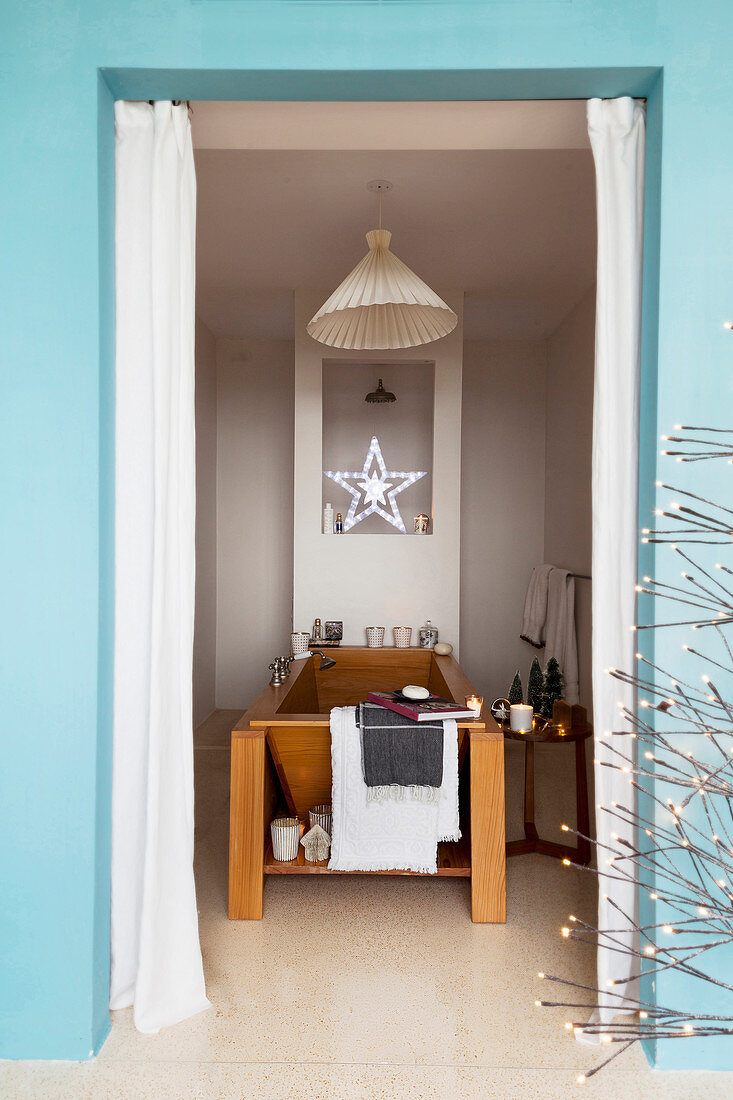 View into festively decorated bathroom with modern wooden bathtub