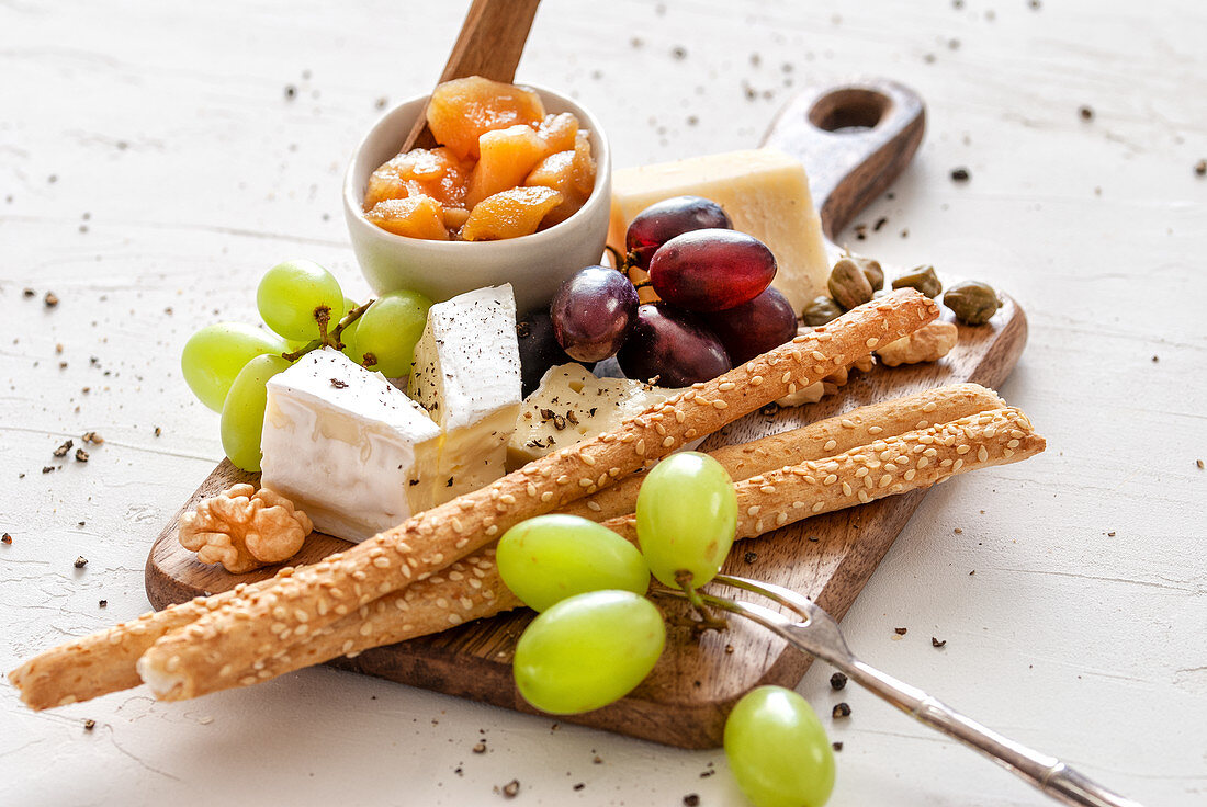 Cheese platter with apple chutney, nuts, capers, grapes and breadsticks