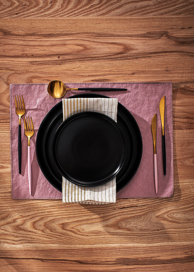Elegant place setting with black plates and gold cutlery