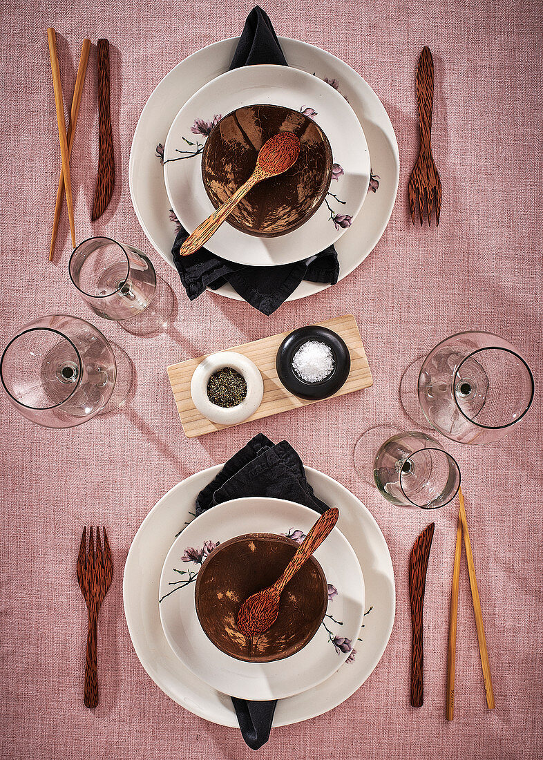 White place settings with coconut shells, chopsticks and wooden cutlery