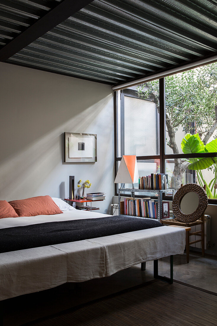 Double bed, bedroom bench and bookshelves below window in bedroom