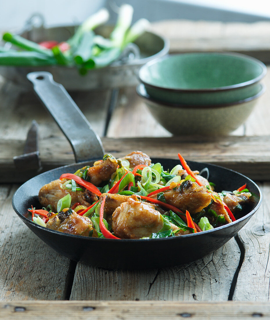 Chicken wings with spring onions in a wok