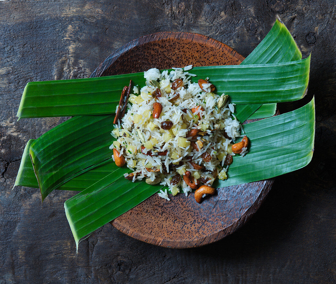 Rice with fruits and nuts served on banana leaves