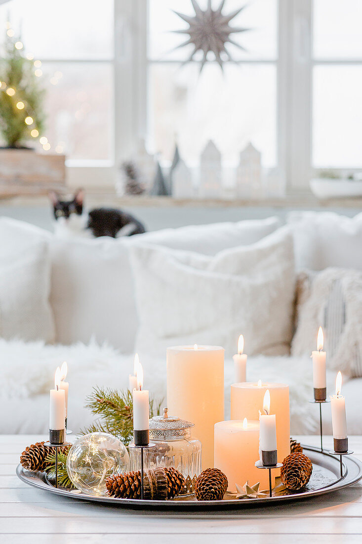 Arrangement of candles on tray and Christmas decorations in living room