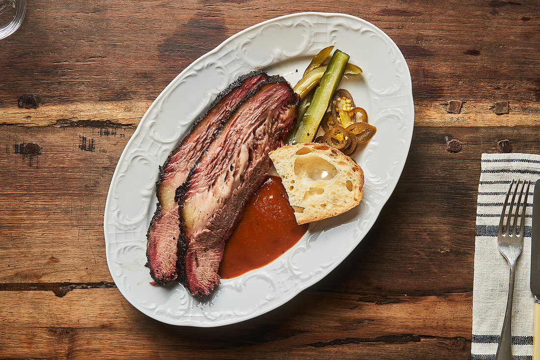 Meat with piece of bread and ketchup on plate on table