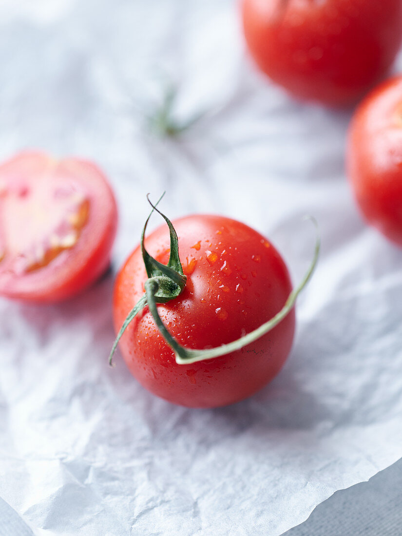 Frische Tomaten, ganz und halbiert auf Papier