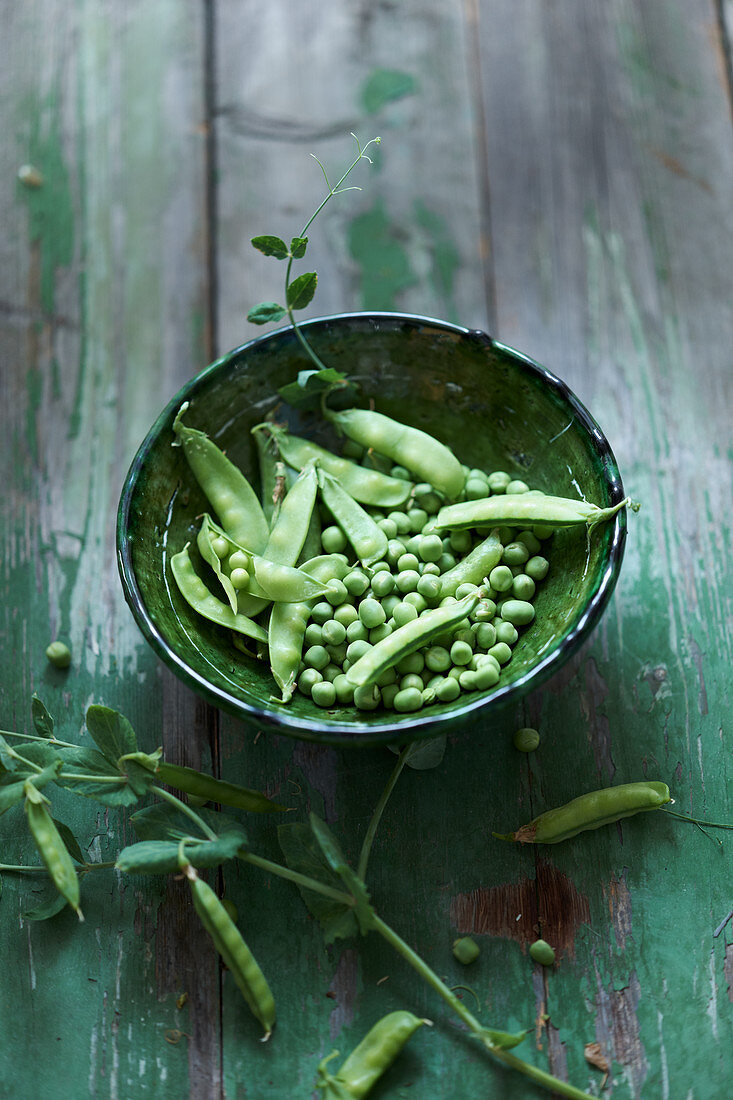 Fresh peas in a green ceramic bowl