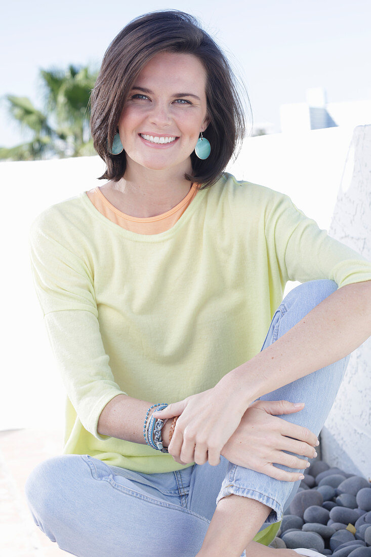 A young woman wearing an apricot top, a yellow jumper and jeans