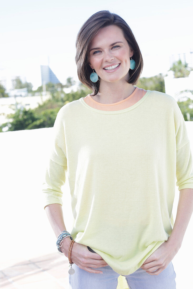 A young woman wearing an apricot top, a yellow jumper and jeans