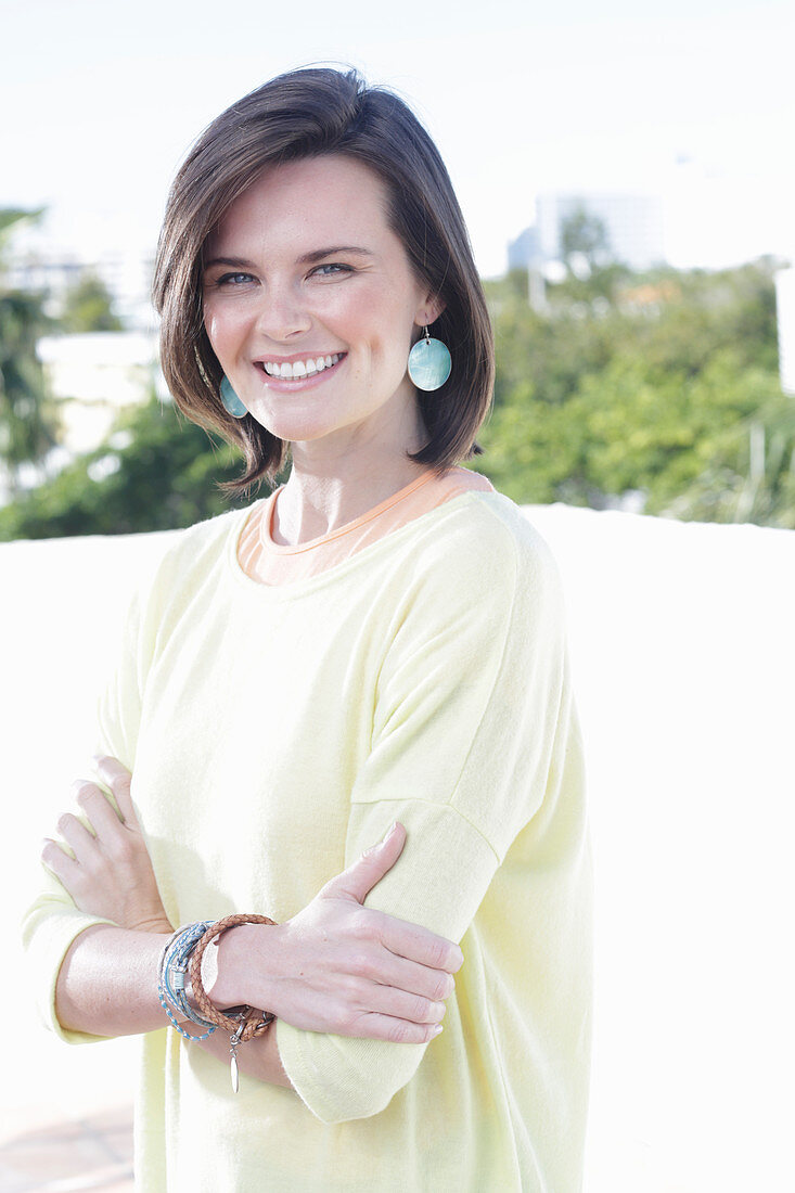 A young woman wearing an apricot top and a yellow jumper