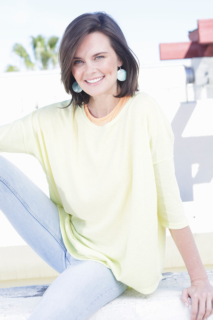 A young woman wearing an apricot top, a yellow jumper and jeans