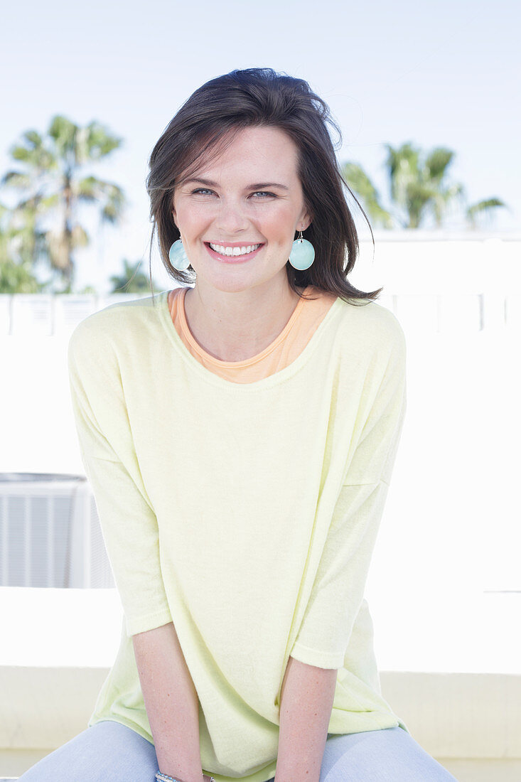 A young woman wearing an apricot top, a yellow jumper and jeans