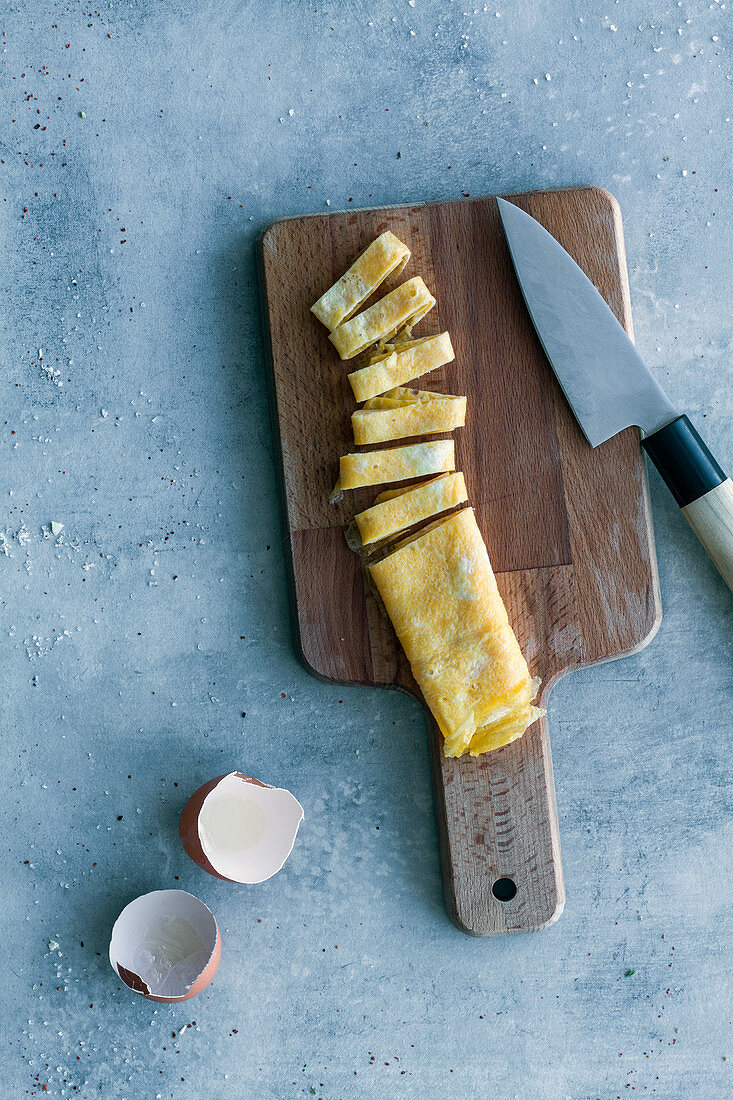 Fresh cut egg omelet with egg shells and knife on table