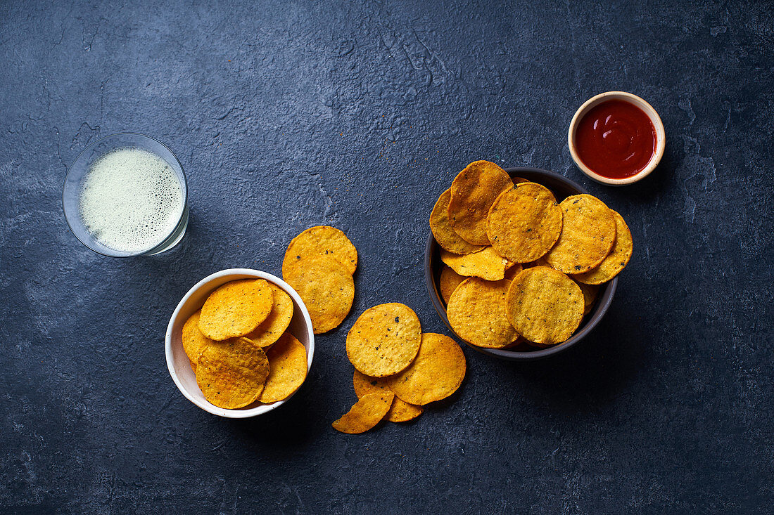 Mexican round-shaped nacho chips in bowls with hot chili salsa and a glass of beer