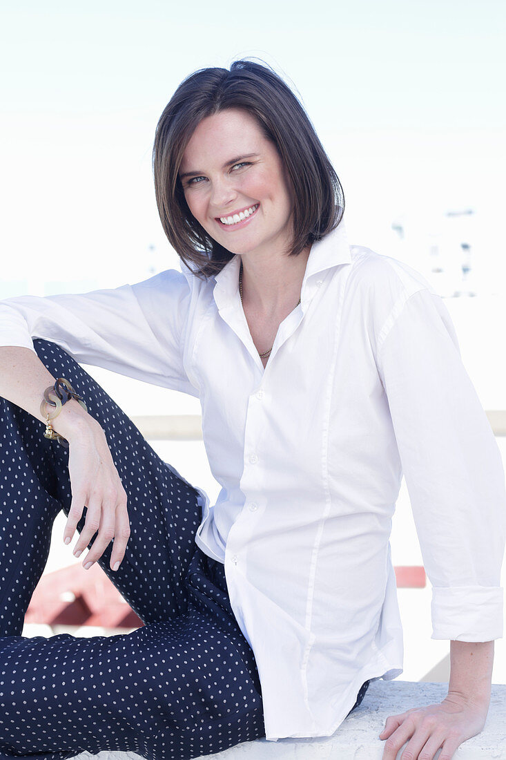 A young woman wearing a white shirt and polka dot trousers