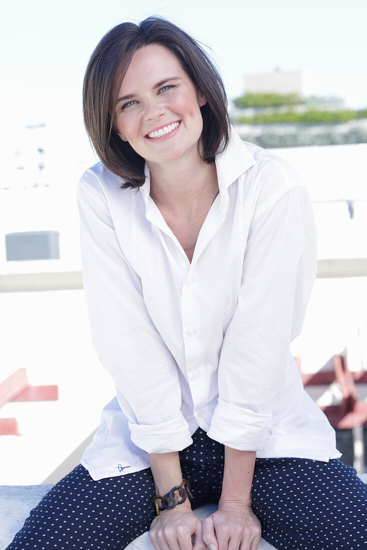 A young woman wearing a white shirt and polka dot trousers