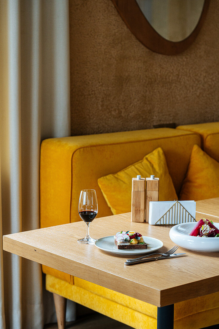 Dishes and glass of red wine placed on table during dinner in luxury cafe