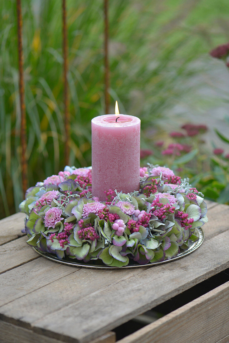 A wreath of candles made from hydrangea blossoms, autumn chrysanthemums, bell heath, and snowberries