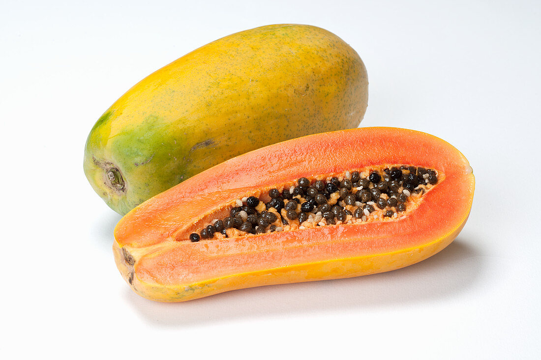 Papaya, ganz und halbiert auf weißem Untergrund