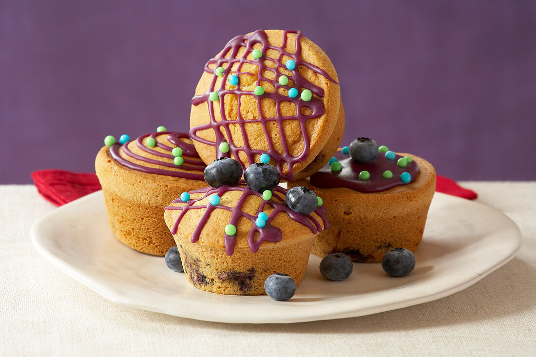 Muffins mit lila Glasur und Heidelbeeren