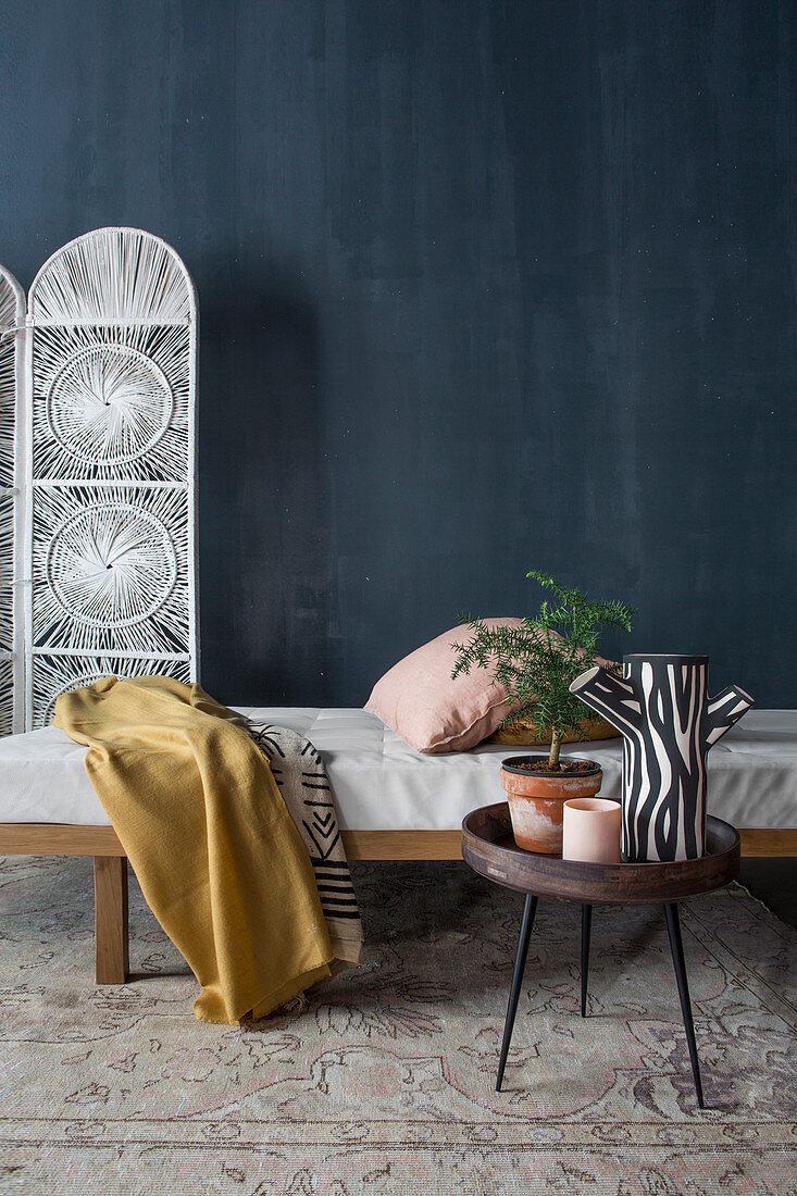 Side table and couch in front of screen and dark blue wall