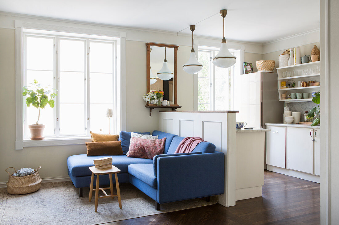 Blue sofa against partition wall screening open-plan kitchen