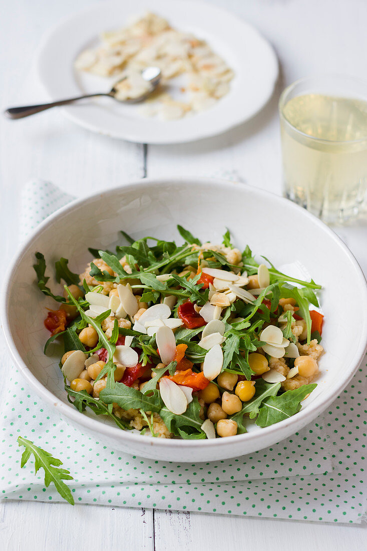 Salad made of rocket, roasted pepper, chickpeas and almonds, almond flakes, white wine