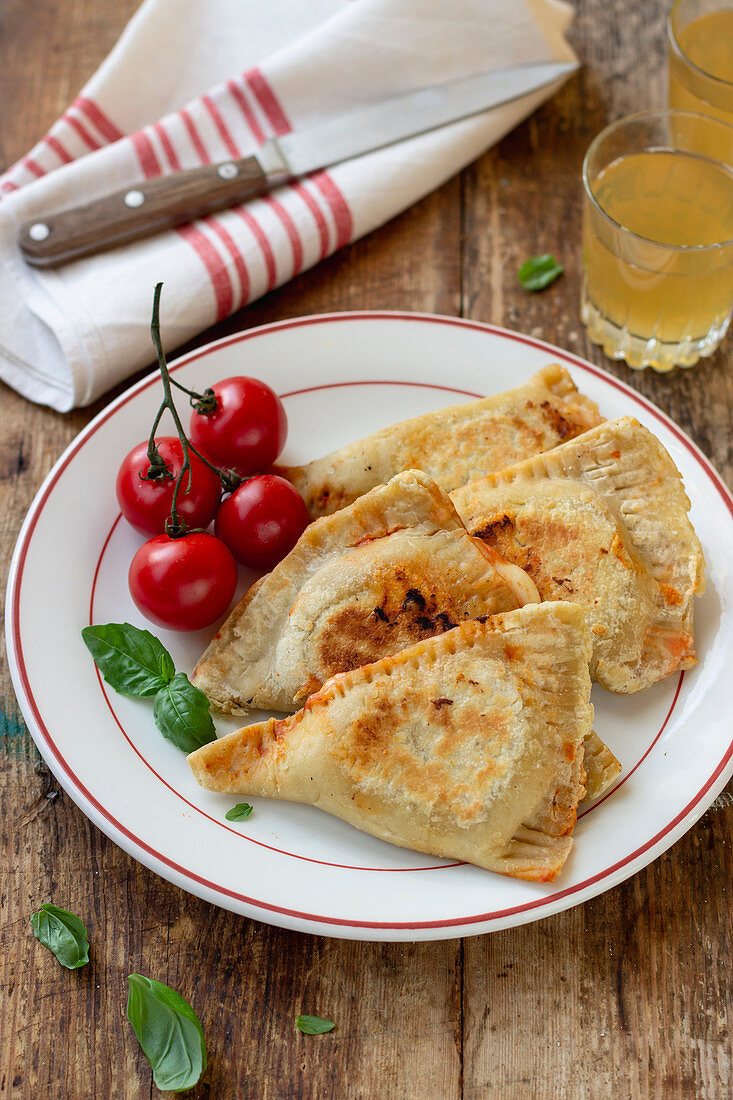 Mini calzone with tomato sauce, mozzarella, basil, cherry tomatoes, apple juice