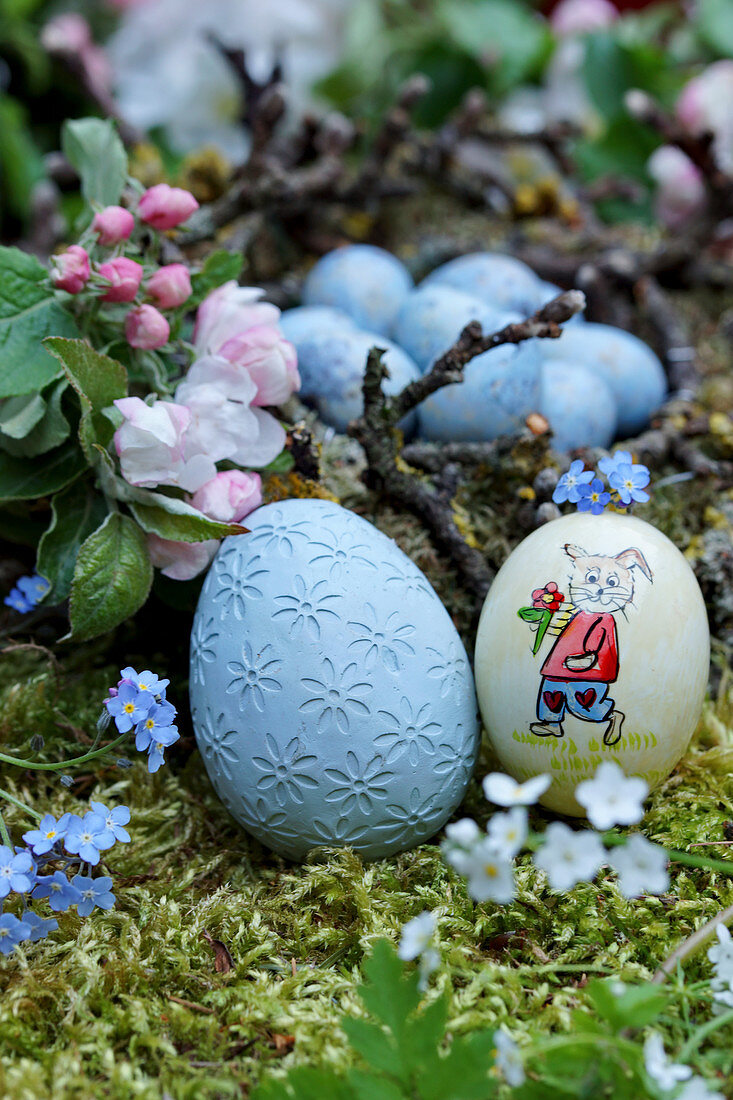 Easter eggs on bed of moss next to apple blossom