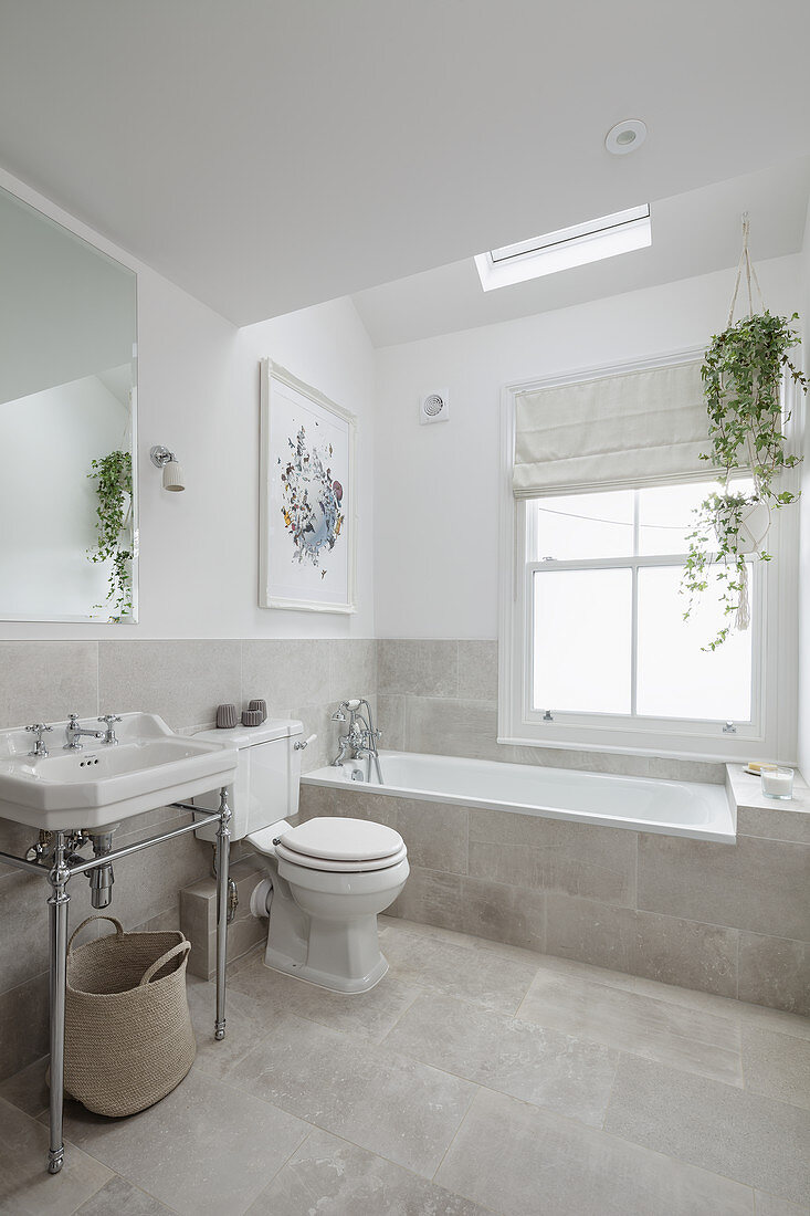 Vintage-style washstand, toilet and fitted bathtub below skylight in bright bathroom
