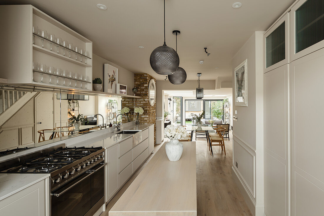 White kitchen with narrow island counter in elongated open-plan interior