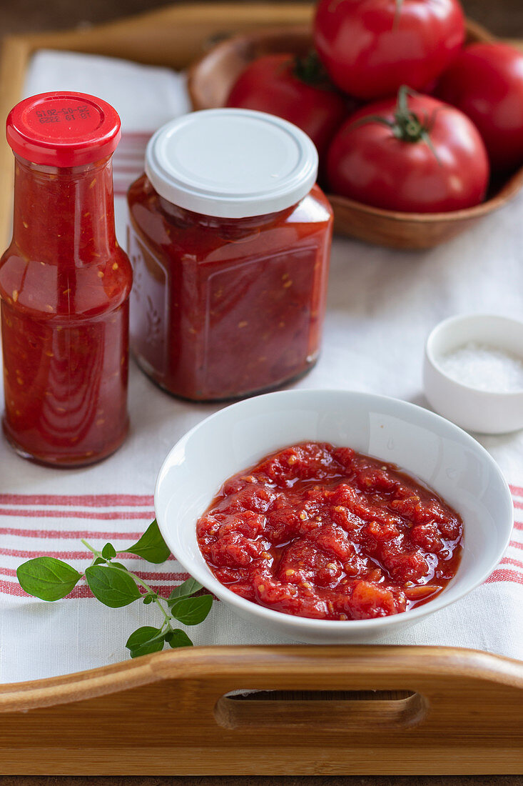 Homemade tomato puree in a ball and in jars, fresh tomatoes