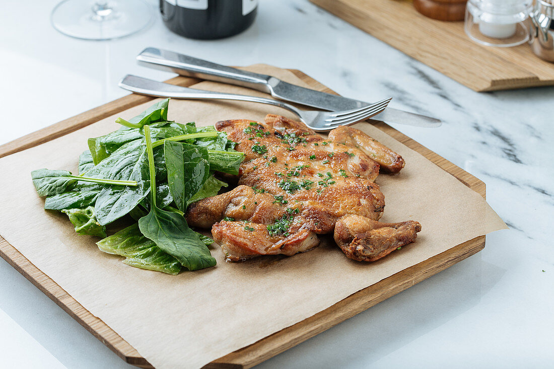 Fried golden chicken and herbs on wooden board with basil leaves