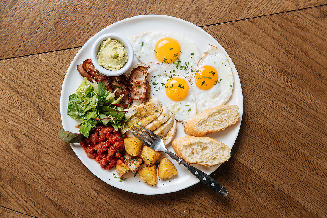 Englisches Frühstück mit Spiegeleiern, Speck, Toast und Gemüse