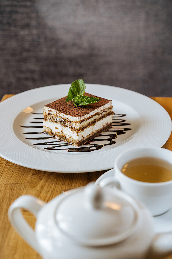 Chocolate tiramisu decorated with green and poured with syrup and tea