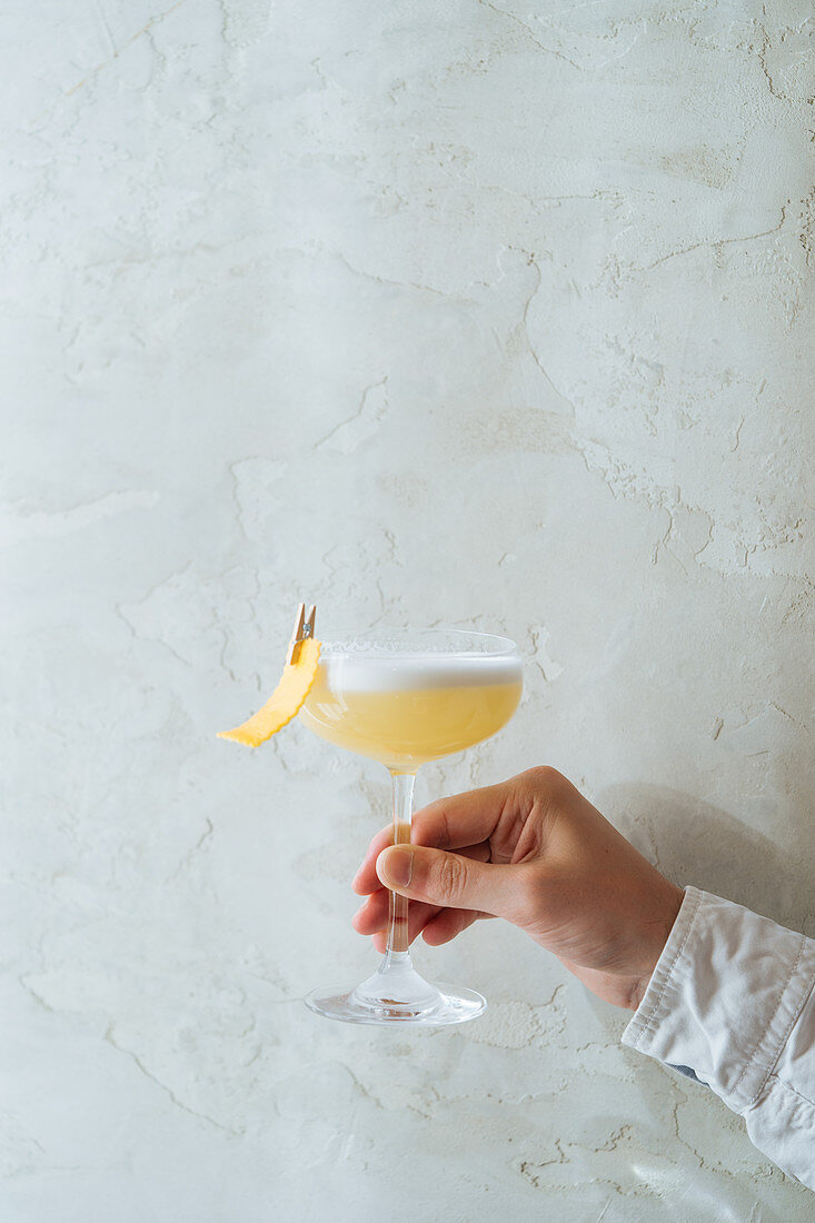 Cropped person holding fresh appetizing cocktail in glass festively decorated with clothespin