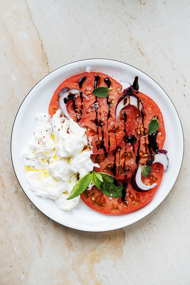 Tomato carpaccio with stacciatella, red onions and balsamic cream