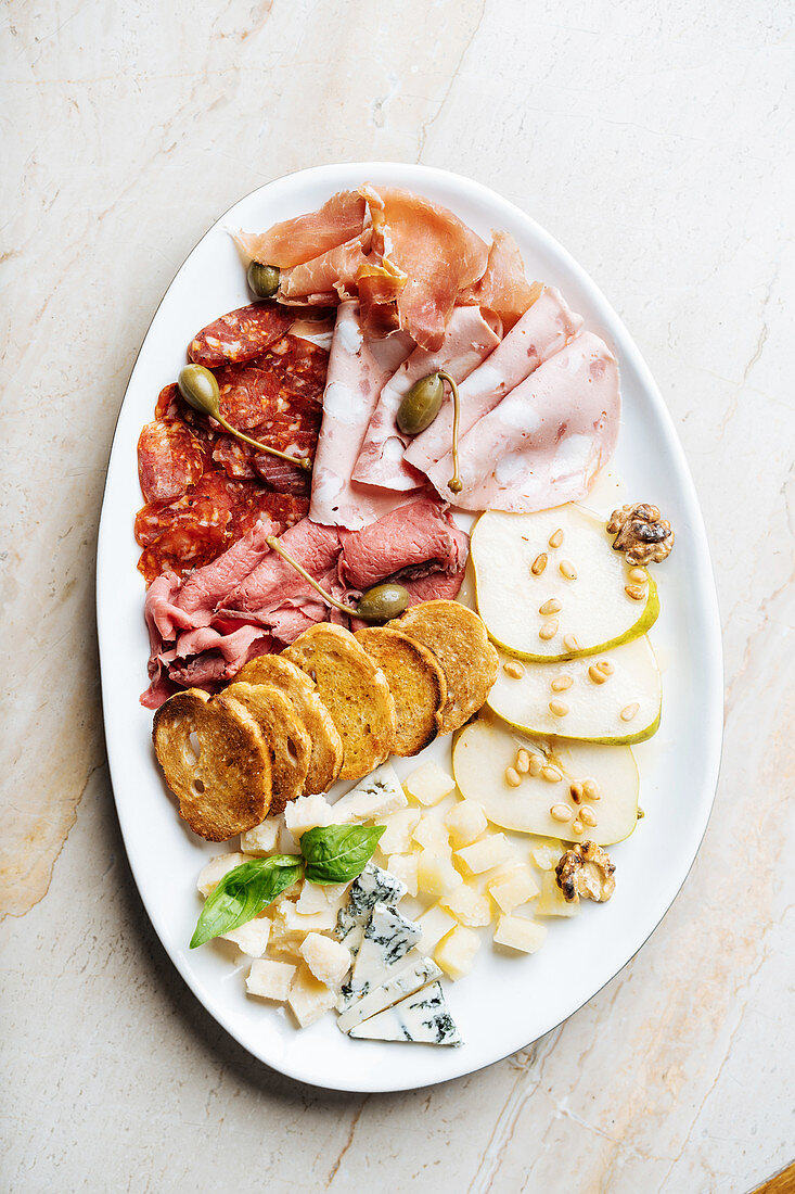 Wurst-Käse-Platte mit Kapernäpfel, Röstbrot, Birnenscheiben und Nüsse