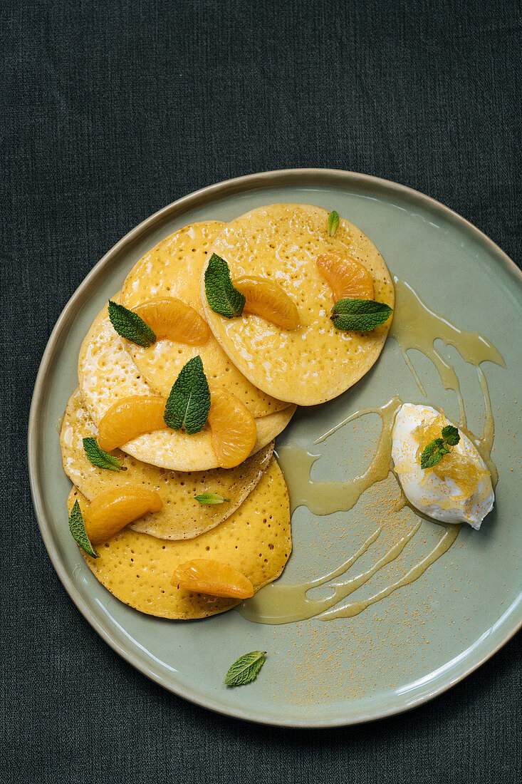 Pancakes with slices of tangerine leaves of mint served with sauce