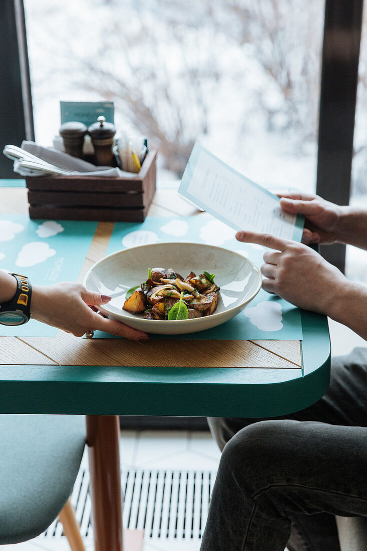 Kellnerin serviert Gericht auf Restauranttisch