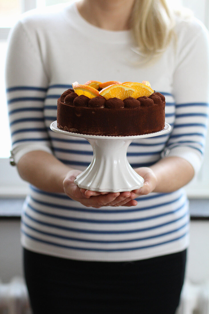 Frau hält Schokoladenkuchen mit Orangen