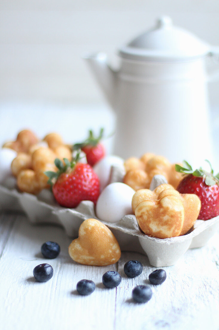 Small heart pancakes with berries and eggs in an egg box