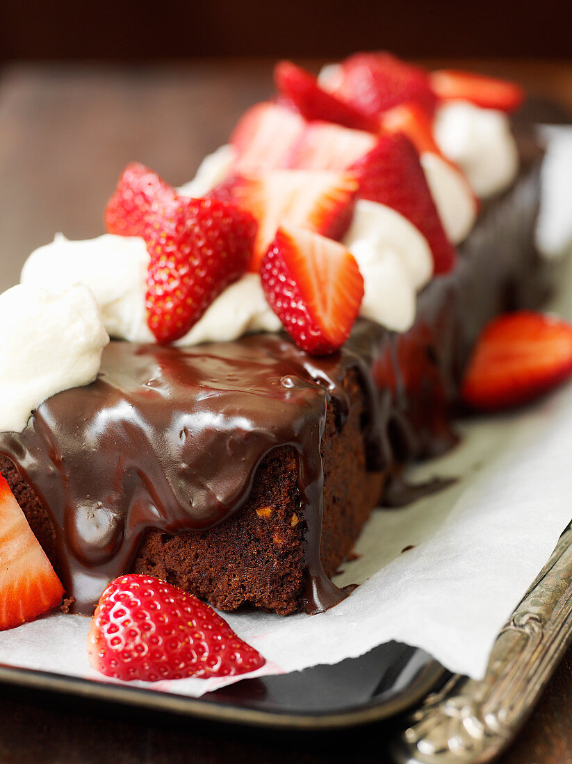 Schokoladen-Kastenkuchen garniert mit Ganache und Erdbeeren