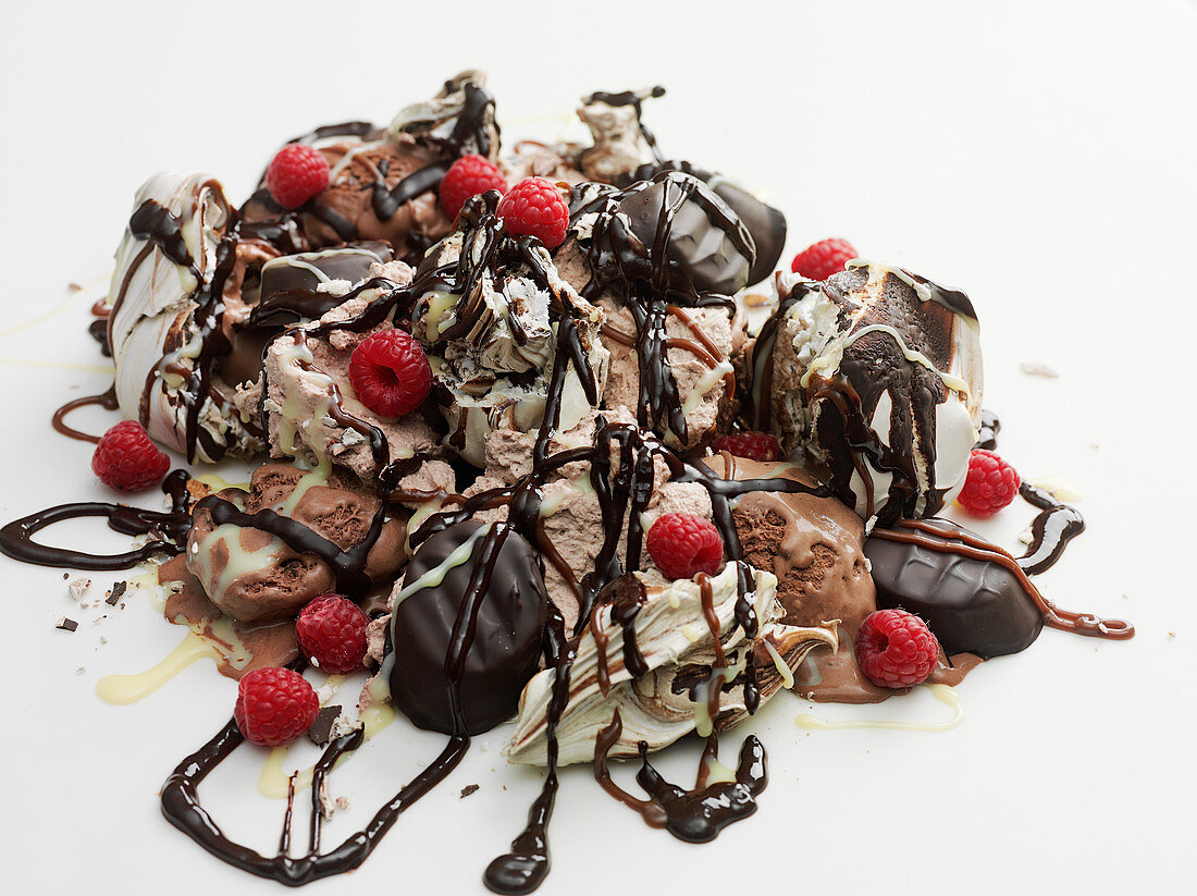 Ice cream piled with confectionery, chocolate sauce and raspberries
