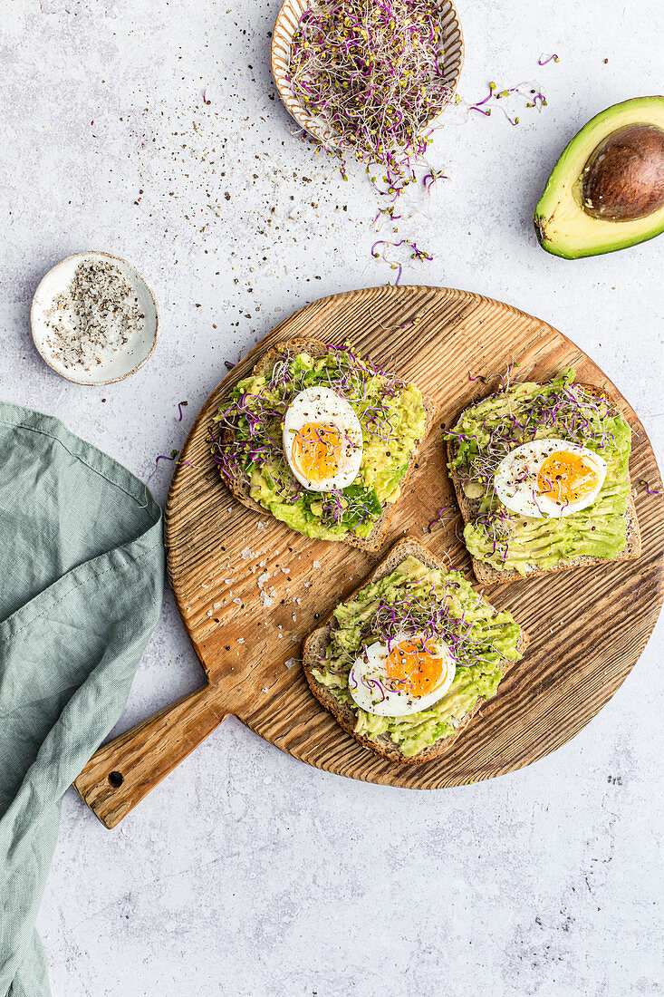 Avocado and medium boiled egg sandwitch served with salt, pepper and radish sprouts