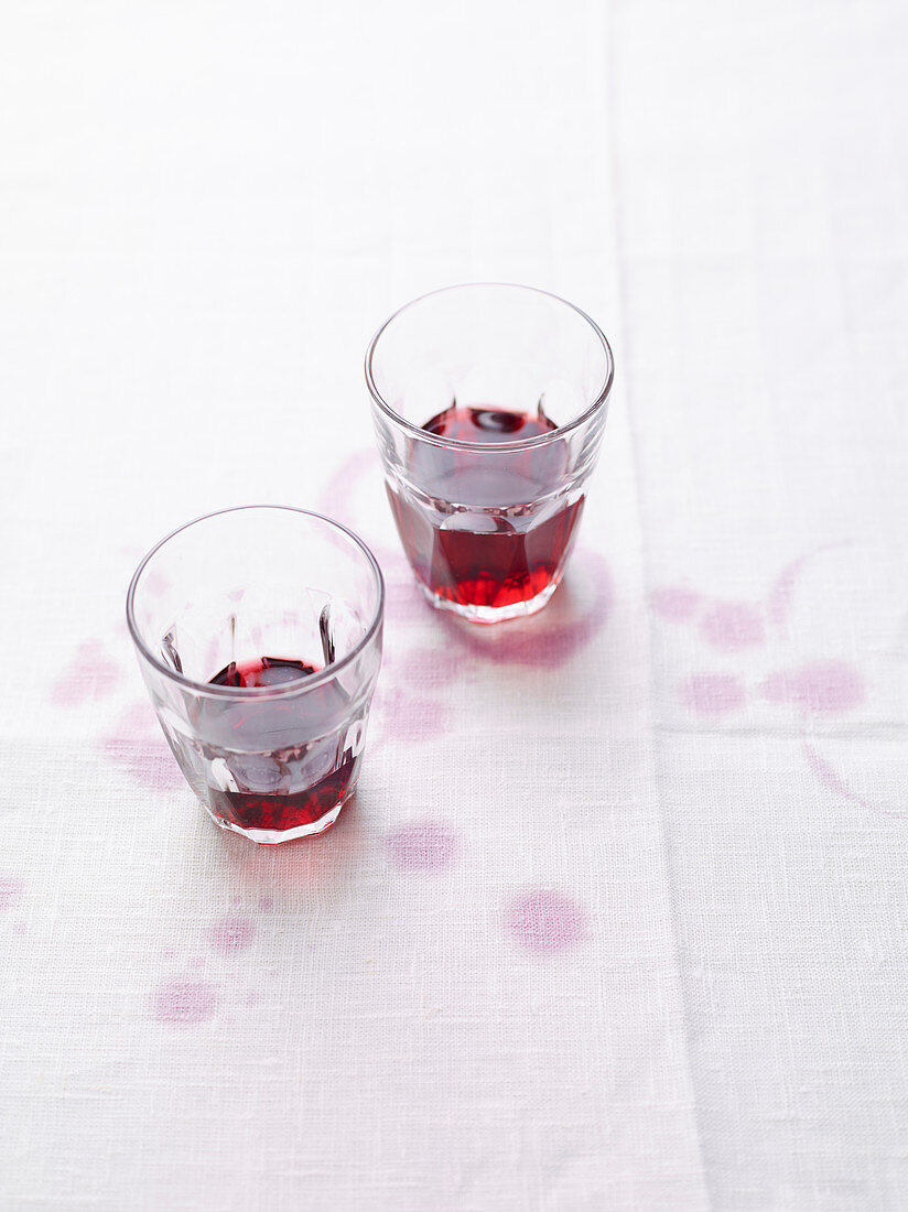 Rotweinstilleben mit Rotweinflecken auf weisser Tischdecke