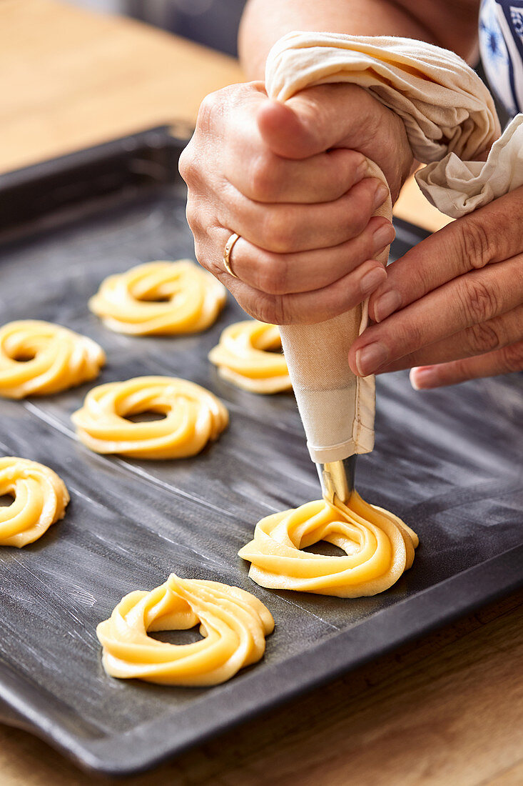 Choux pastry being piped on a baking tray