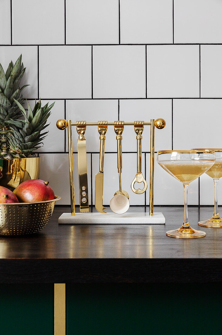 Golden cocktail utensils hung on stand in kitchen